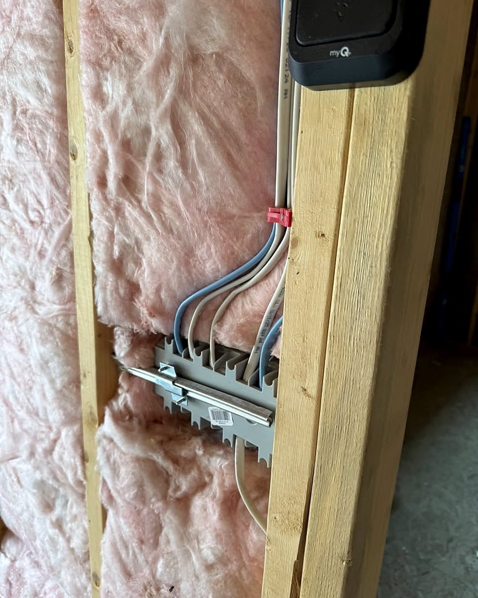 Low voltage cables dressed through a bracket and protected by a nail plate in a framed wall