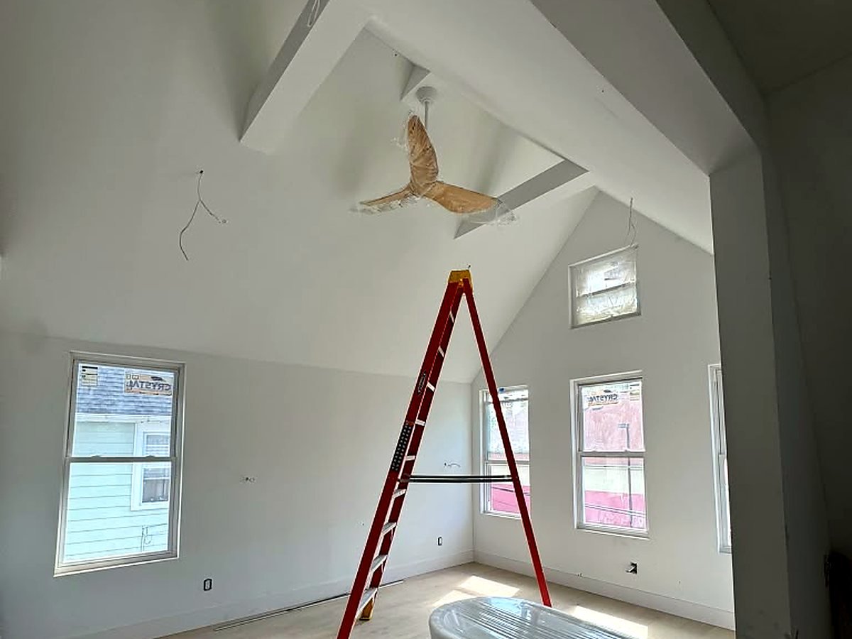 Ceiling fan newly installed on a vaulted ceiling with exposed beams in a home under construction