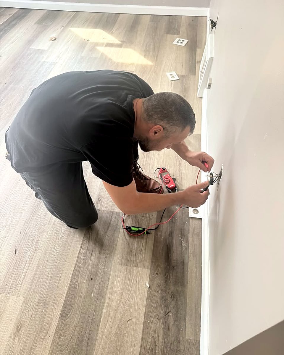 Raber Electric electrician testing a receptacle with a clamp meter during a safety inspection